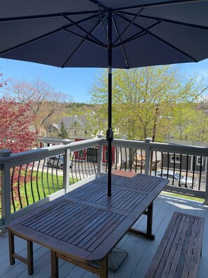 Eine Holzterrasse mit Tisch und Sonnenschirm.