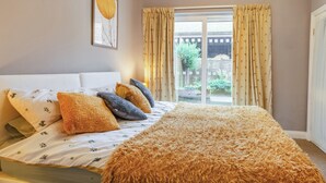 A bedroom with a bed, pillows, a fluffy rug, a window with curtains, and a framed picture on the wall. - 3 bedroom accommodation in Thornholme, near Driffield (Thornholme, near Driffield)