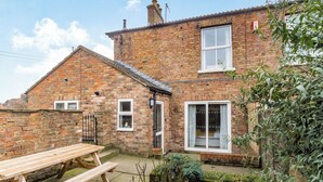A two-story brick house with a wooden bench in the front yard. - 3 bedroom accommodation in Thornholme, near Driffield (Thornholme, near Driffield)