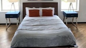 Ein Schlafzimmer mit einem großen Bett, zwei Nachttischen, einem Kopfteil und einem Gemälde an der Wand.