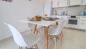 Eine moderne Küche mit weißen Schränken, einem weißen Kühlschrank und einer blauen Toastmaschine.