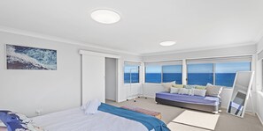 Een slaapkamer met een bed, een zithoek en uitzicht op de oceaan.