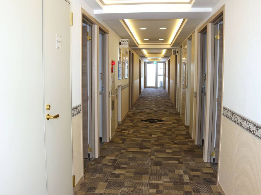A hotel corridor with a checkered floor, doors on both sides, and a sign indicating a VOD room.