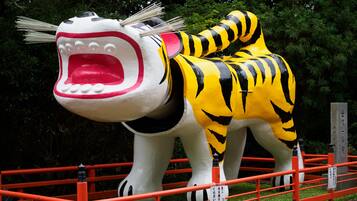 A large sculpture of a tiger with a human face, standing behind a red fence.