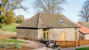 A stone cottage with a tiled roof, a wooden door, and a small garden area. - Pipistrelle - UK30758 (Bream, near Lydney)