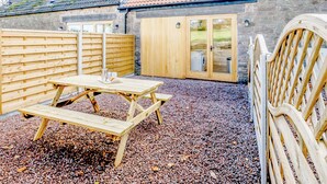 A wooden deck with a picnic table, a wooden fence, and a stone building with a tiled roof. - Pipistrelle - UK30758 (Bream, near Lydney)