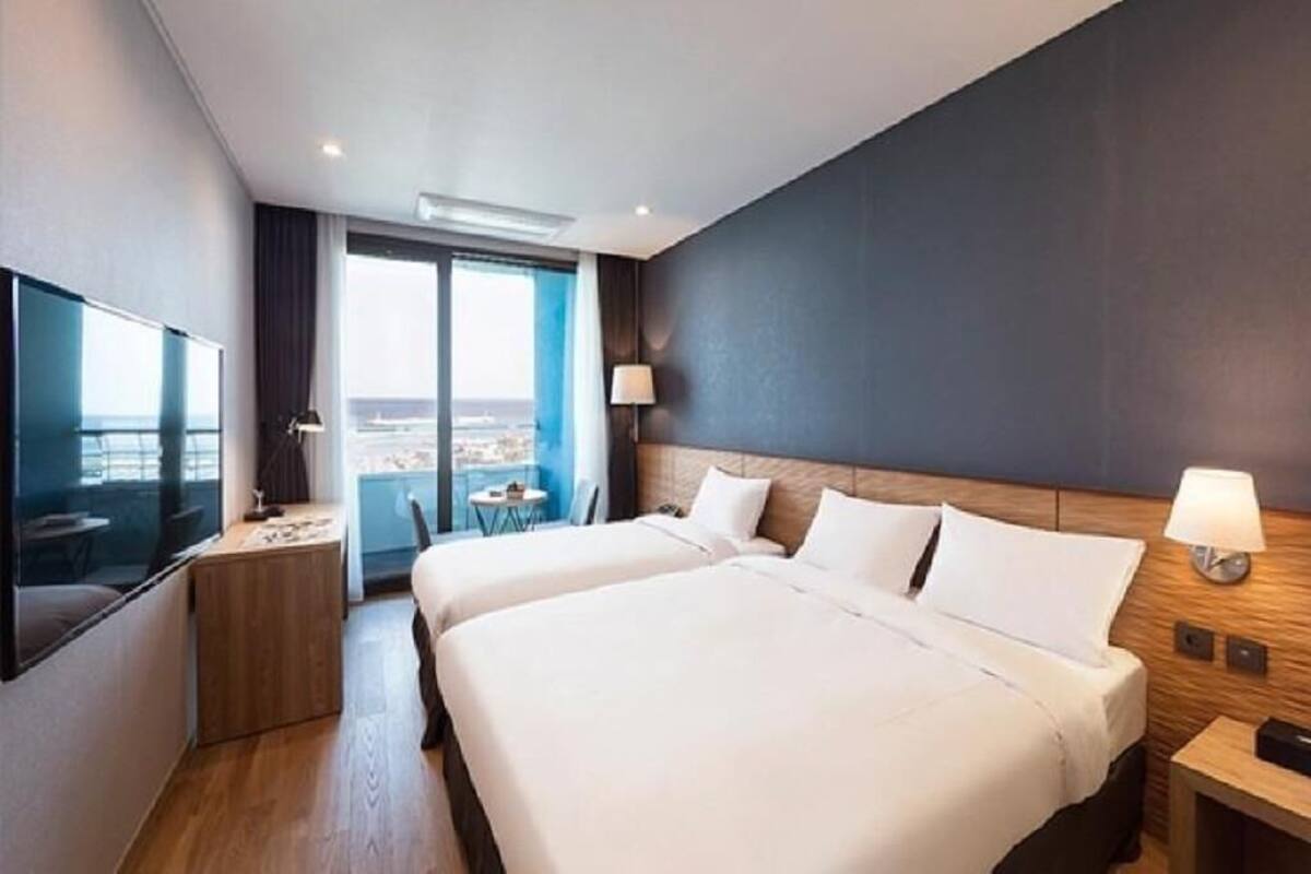 Een moderne hotelkamer met twee bedden, een televisie, een bureau en uitzicht op de stad.