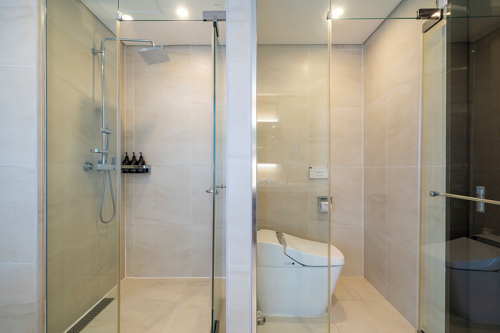 Ein modernes Badezimmer mit einer gläsernen Duschkabine, Toilette und einer Glasabtrennung.