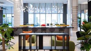 A modern bar area with a long counter, multiple seating options, and a view of the city through large windows. - SL Hotel Gangneung (Gangneung)