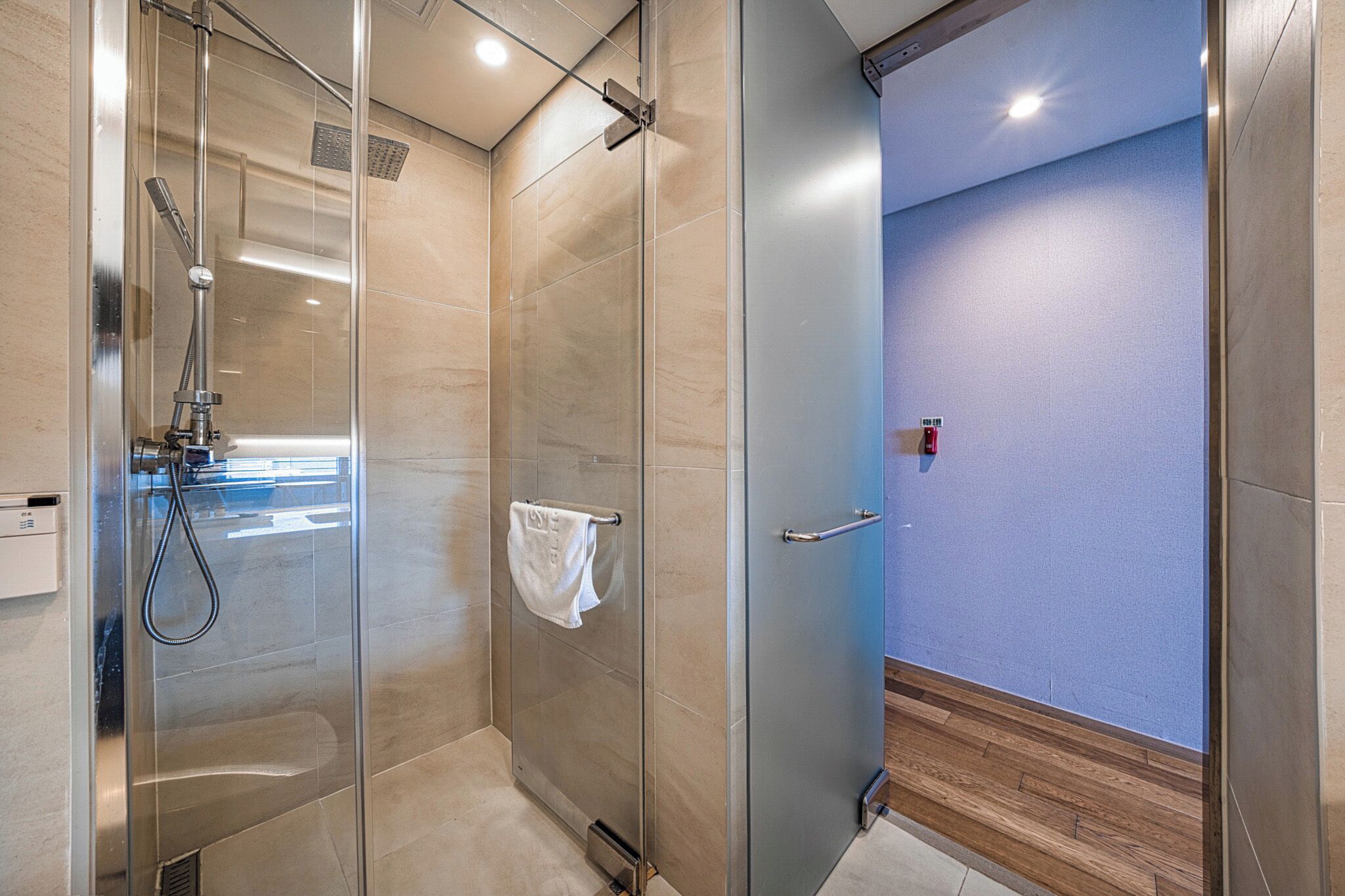 Un baño moderno con ducha envuelta en vidrio, un perchero y una pared azul.