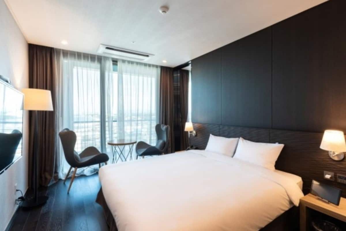 Een moderne hotelkamer met een groot bed, twee nachtkastjes, een bureau en een stoel.