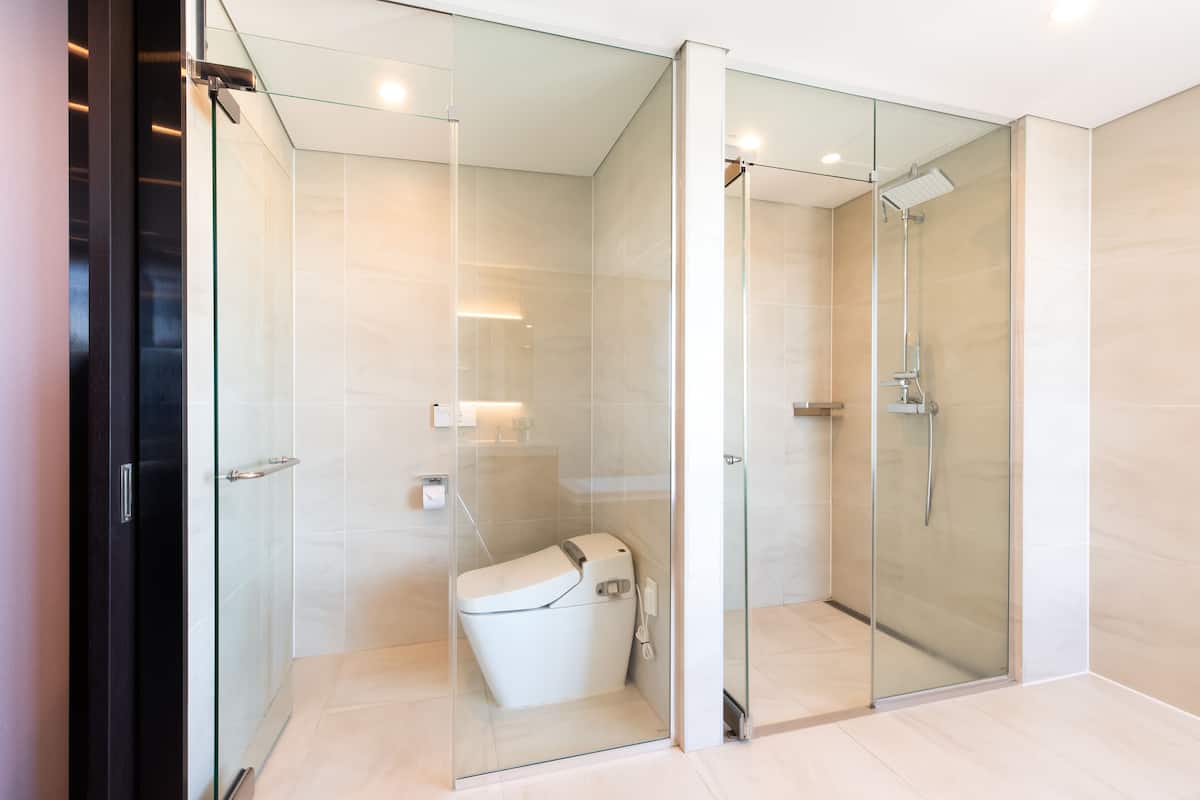 Een moderne badkamer met een douchecabine van glas, een toilet en een wastafel.