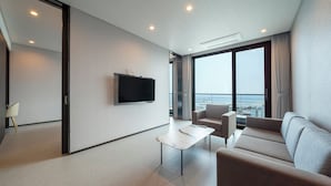 A modern hotel room with a large window, a flat-screen TV, a sofa, a coffee table, and a chair. - SL Hotel Gangneung (Gangneung)