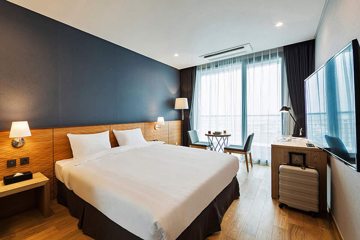 Een hotelkamer met een groot bed, nachtkastjes, een bureau, een stoel en een televisie.