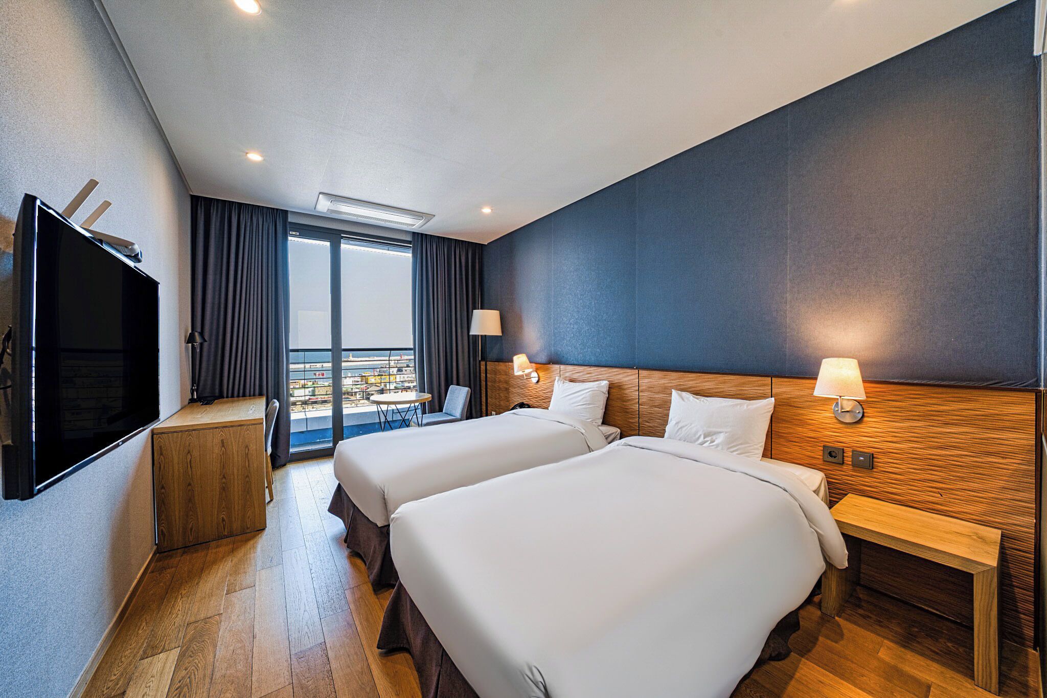 Een hotelkamer met twee bedden, een televisie, een bureau en een balkon met uitzicht.