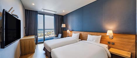 Een hotelkamer met twee bedden, een televisie, een bureau en een balkon met uitzicht.