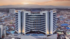 A modern hotel with a curved facade, multiple balconies, and a pool area. - SL Hotel Gangneung (Gangneung)