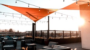 Un patio al aire libre con mobiliario, luces colgantes y una chimenea.