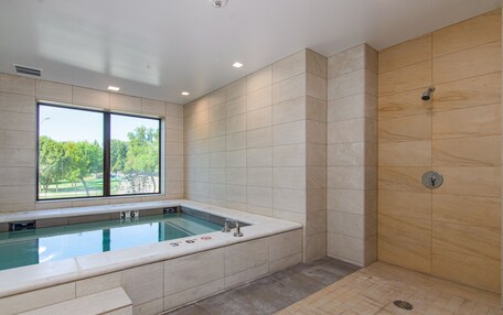 A modern bathroom with a large window, a bathtub, and a shower area.