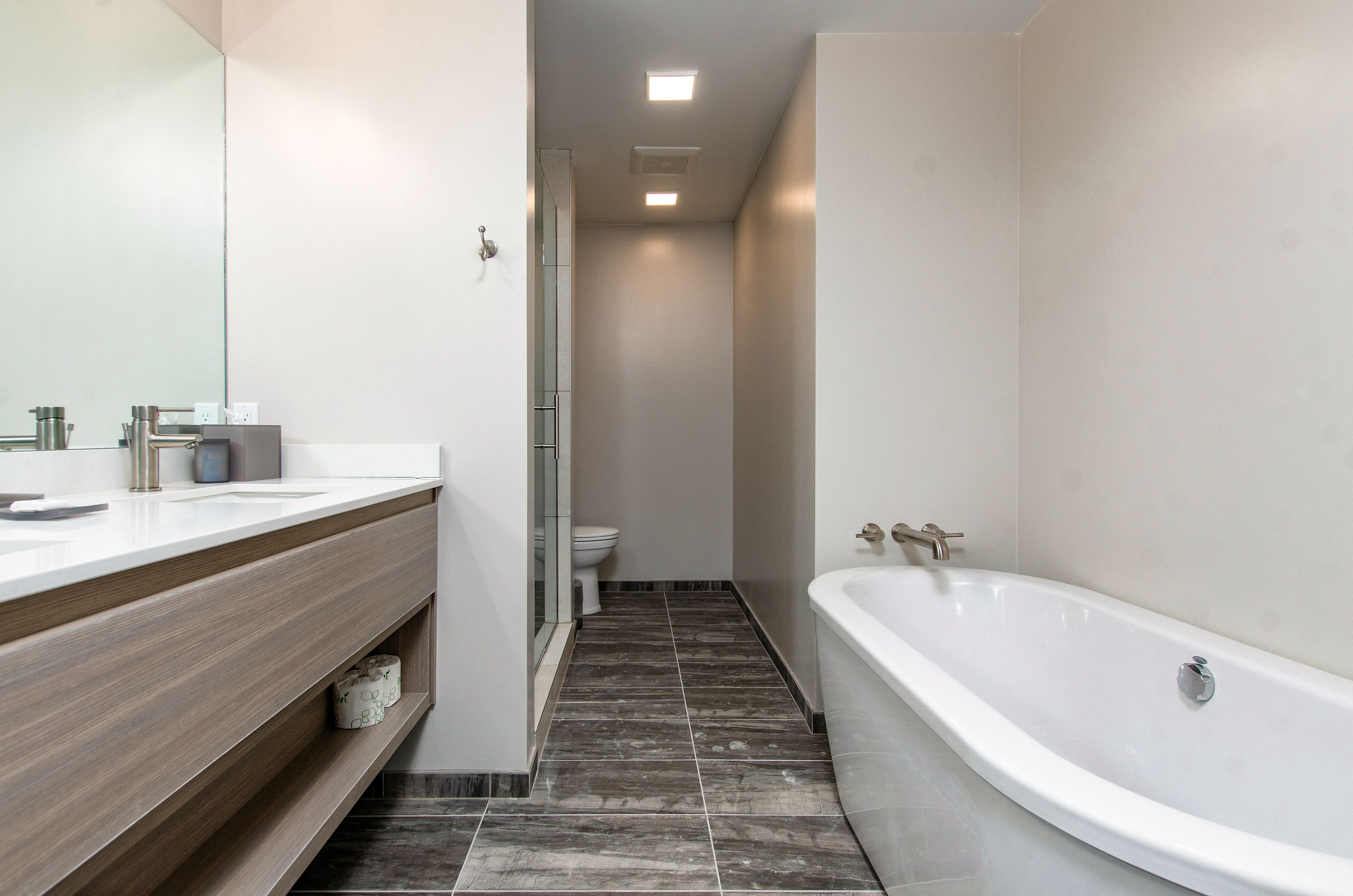 A modern bathroom with a large bathtub, a vanity with a mirror, and a toilet.