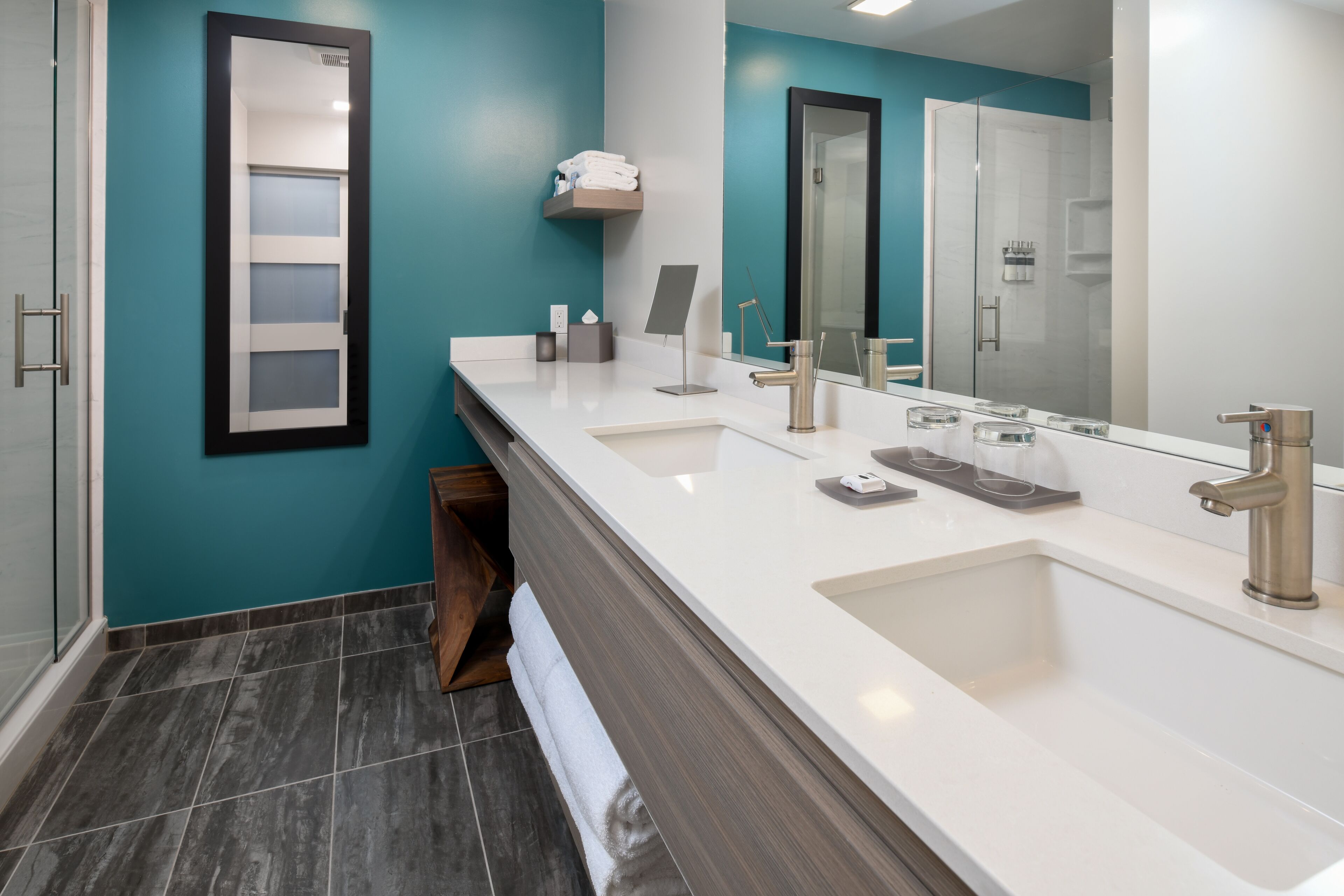 Un baño moderno con un espejo grande, dos lavamanos y una ducha.