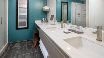Un baño moderno con un espejo grande, dos lavamanos y una ducha.