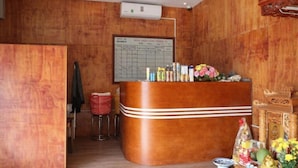 Un mostrador de recepción con detalles de madera, un tablón de anuncios y un taburete pequeño.