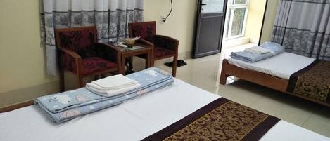 A hotel room with two beds, a TV mounted on the wall, and a small table with chairs.