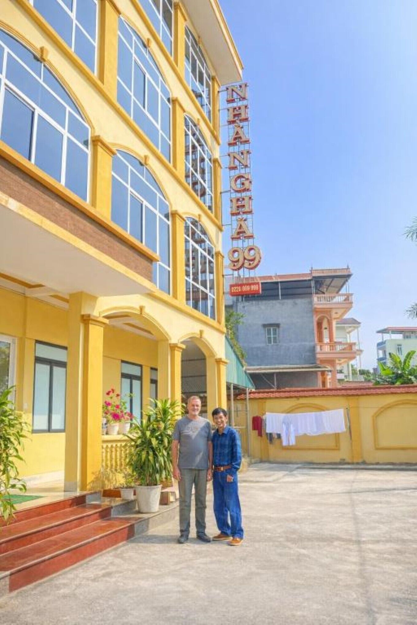 Un edificio con un letrero que dice 'NHANH CHI 99' y una escalera que conduce a la entrada.