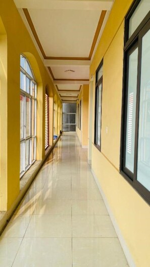 A long corridor with yellow walls, large windows, and a tiled floor. - Hotel 99 (Cao Bang)
