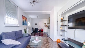 Ein modernes Wohnzimmer mit einer Couch, einem Couchtisch und einem Fernseher an der Wand.