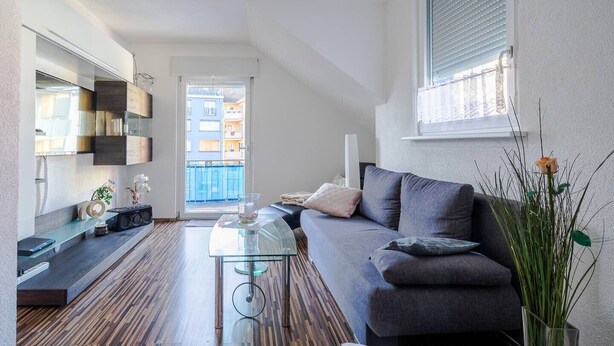 Ein modernes Wohnzimmer mit Sofa, Couchtisch und Blick ins Freie.