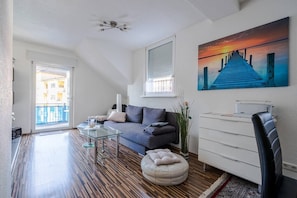 Un salon moderne avec un canapé, une table basse, un pouf et un tableau accroché au mur.