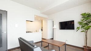 Una sala de estar moderna con un sofá, una mesa, una planta en maceta y un televisor de pantalla plana montado en la pared.