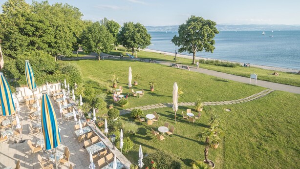Eine Terrasse mit Sitzgelegenheiten im Freien, ein Weg und Blick aufs Meer.