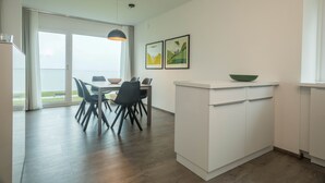Eine moderne Küche mit Essbereich, großen Fenstern und Blick ins Freie.