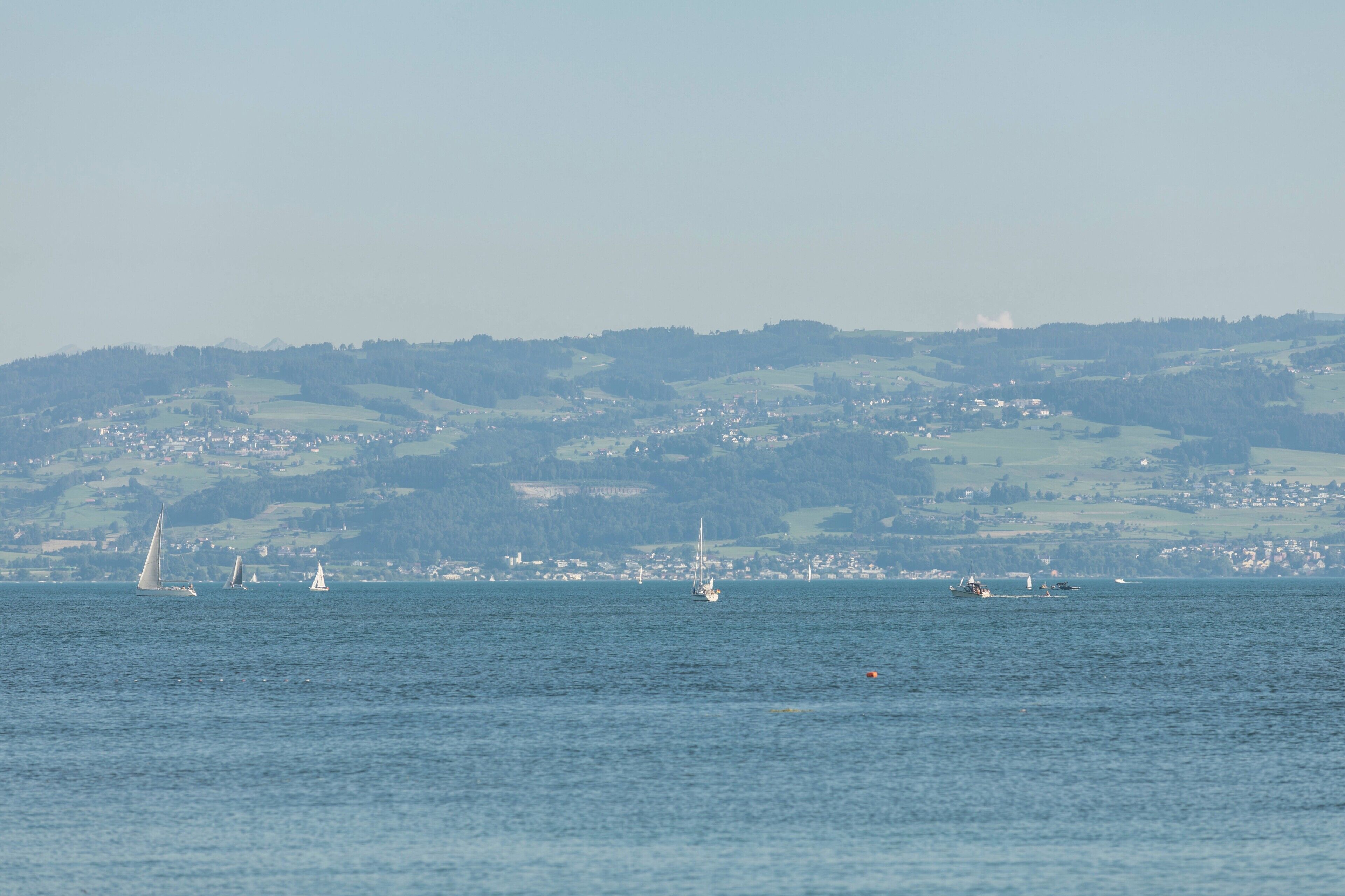 Une vue sur la côte, avec des voiliers sur l’eau et une ville qui se dessine à l’horizon.