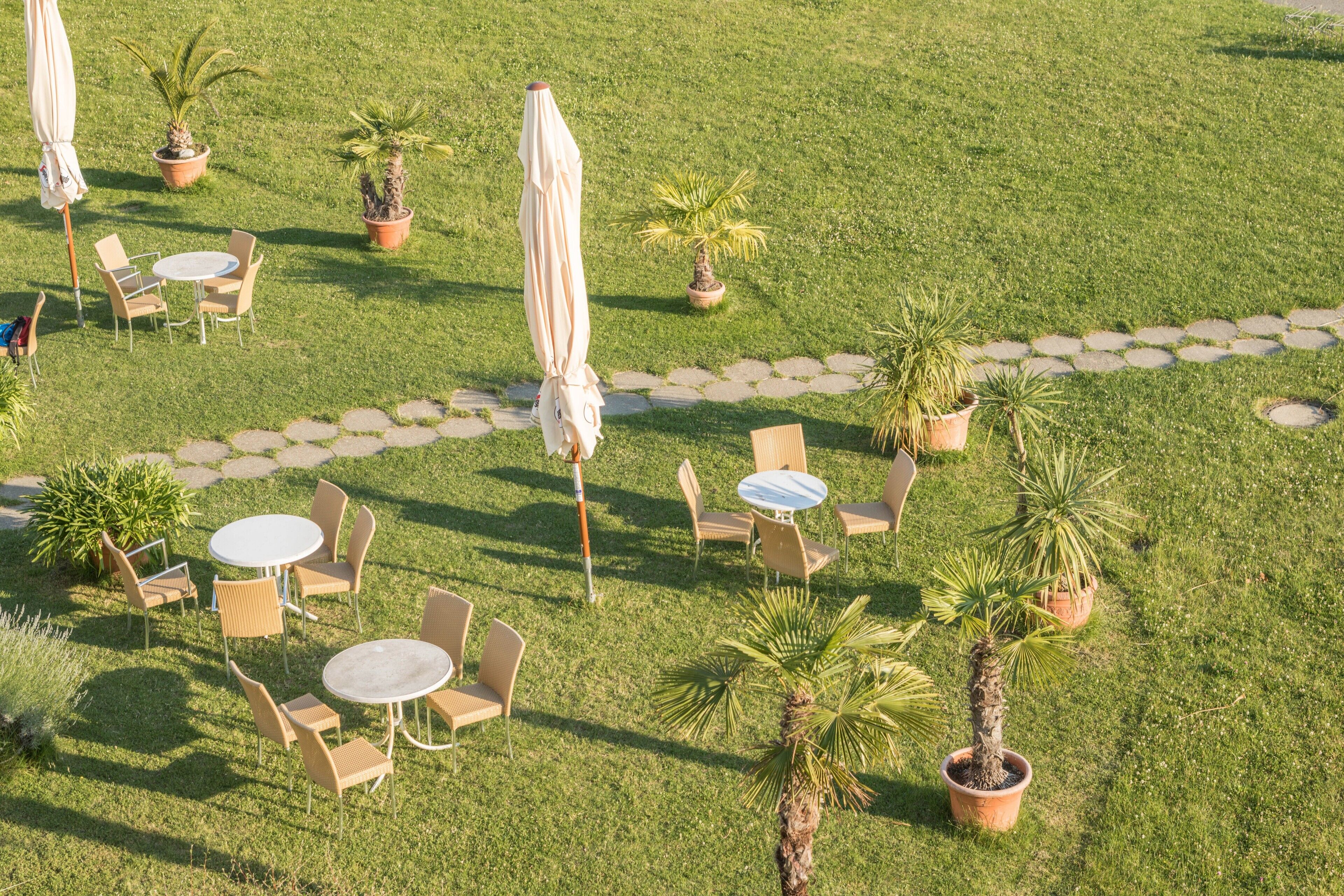 Eine Terrasse mit Sitzgelegenheiten im Freien, Topfpflanzen und einem gepflasterten Weg.