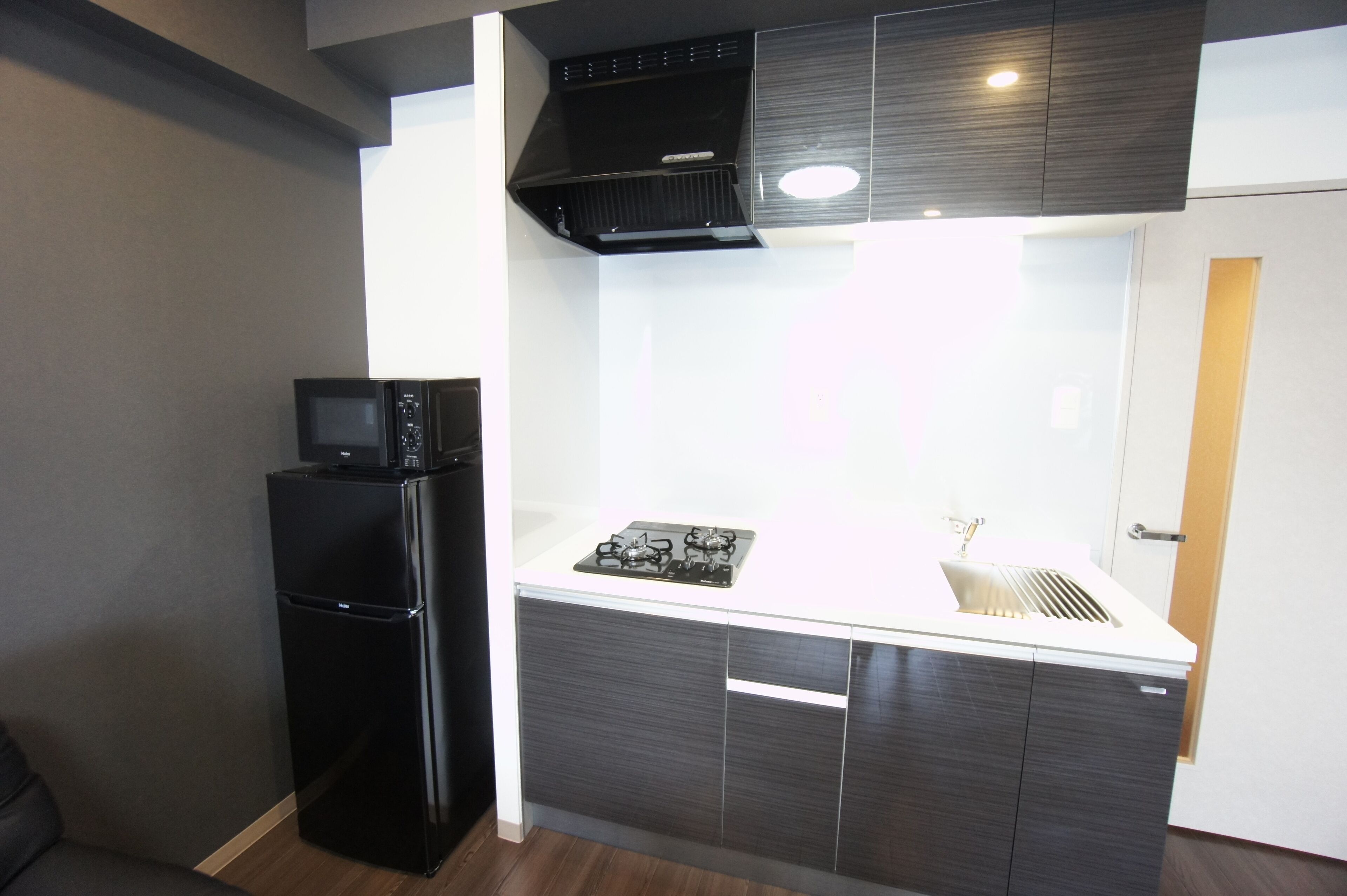 A compact kitchen with a black refrigerator, a stove, and a microwave on the countertop.