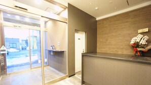 A reception area with a glass door entrance, a reception desk, and a wall-mounted sign. - Piece Eniwa (Eniwa)