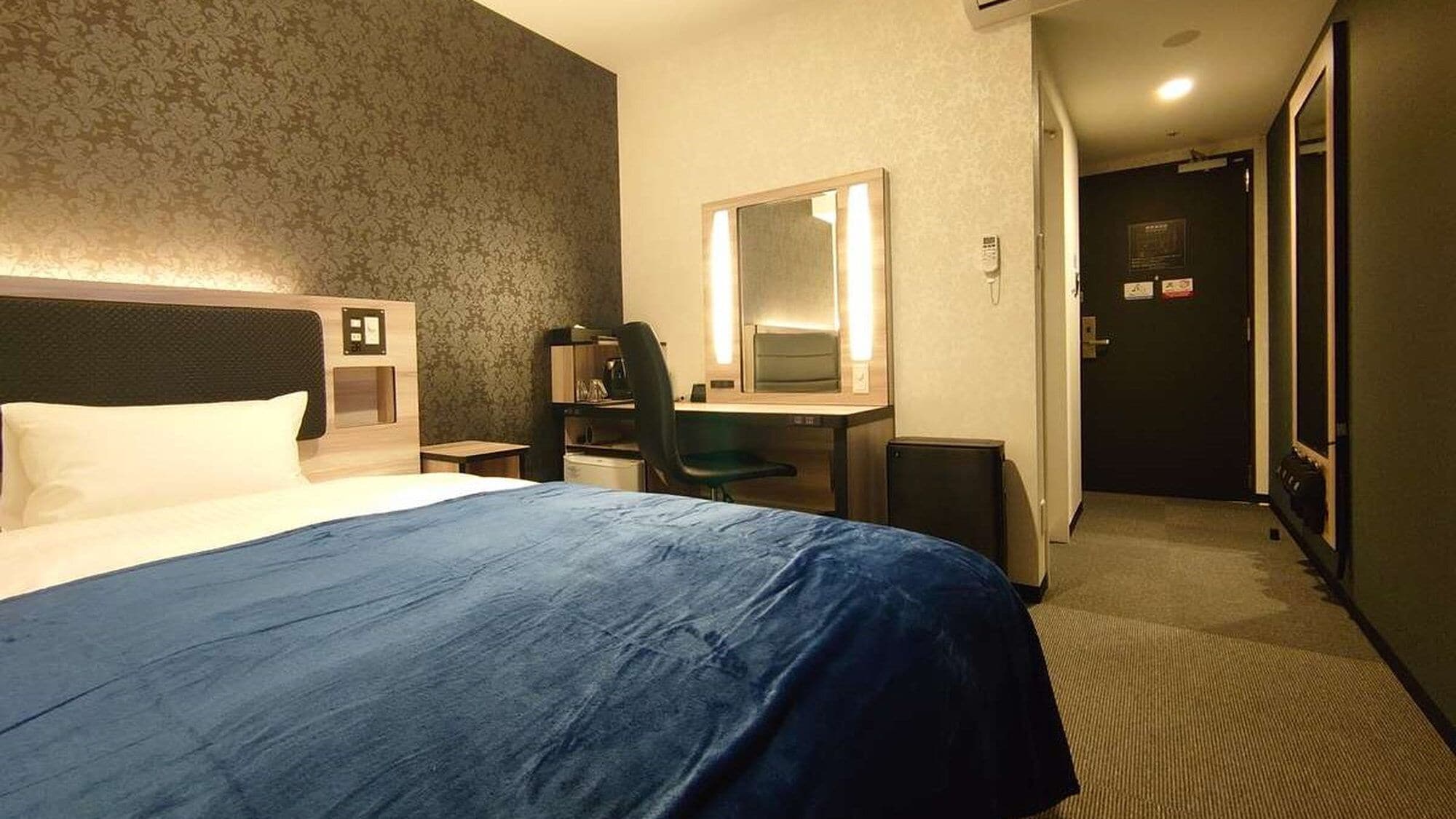Une chambre d’hôtel équipée d’un lit, d’un bureau, d’une chaise et d’un miroir.