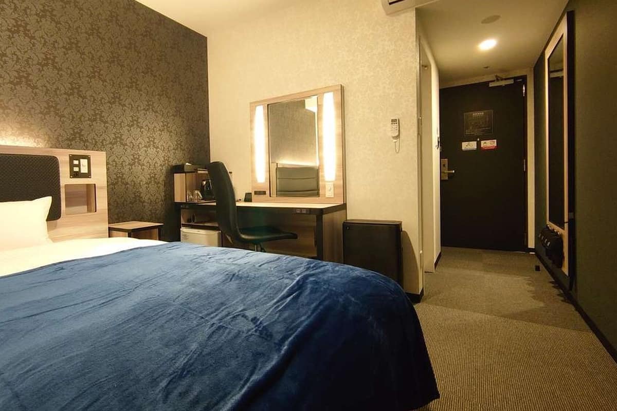 Ein Hotelzimmer mit Bett, Schreibtisch, Stuhl und Spiegel.