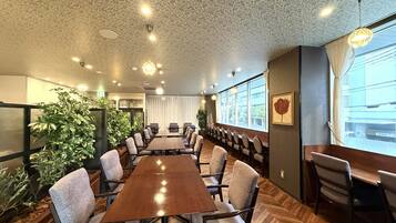 Een vergaderzaal met een lange tafel, stoelen en potplanten.
