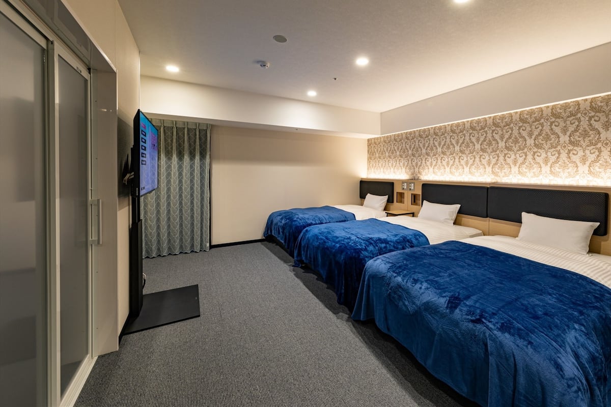 Ein Hotelzimmer mit zwei Betten, einem Fernseher, einem Schreibtisch und einer Wand mit Muster.