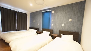 A hotel room with three single beds, wooden headboards, a blue door, and a grey textured wall. - Sakura34 (Sapporo)