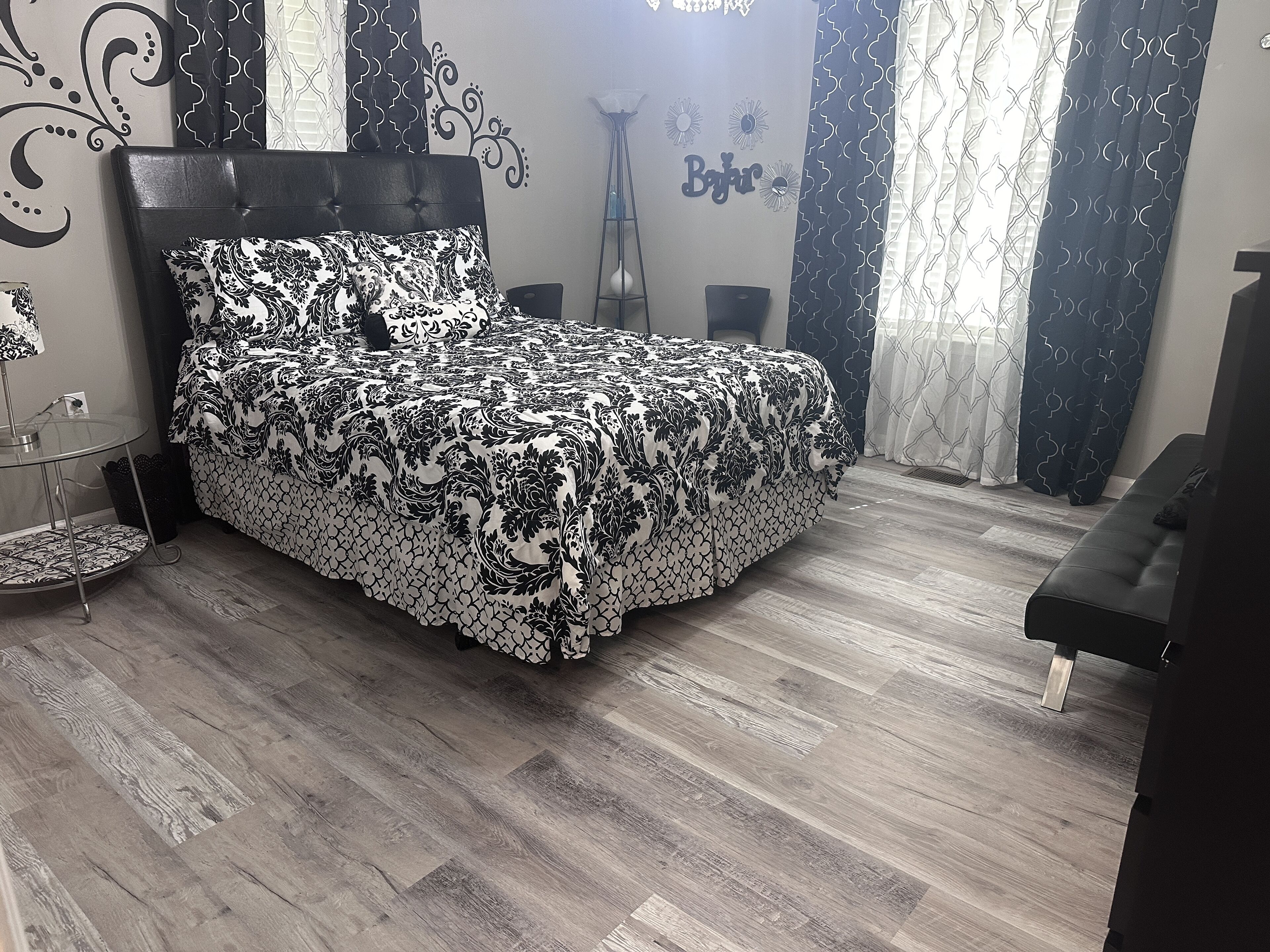 Ein Schlafzimmer mit einem Bett, einem Nachttisch, einer Lampe und einem Sessel.