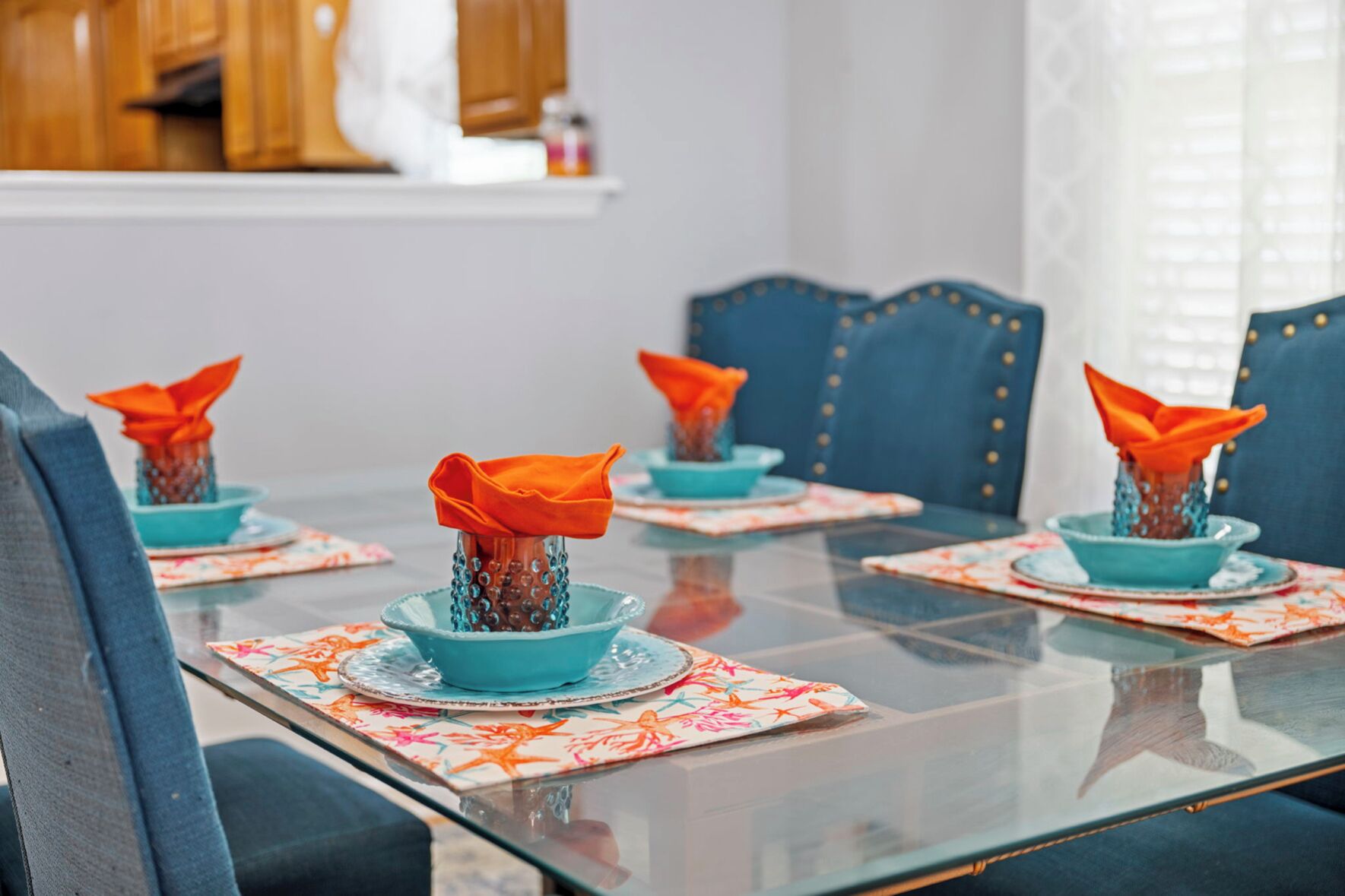 Une table à manger avec des chaises bleues et des serviettes orange.