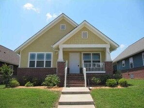 Stunning two-story home with a central entrance, flanked by windows, set amidst a beautifully manicured lawn.