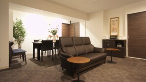 Un salon moderne comprenant un canapé, une table à manger avec des chaises, une petite table ronde, un meuble et une plante.