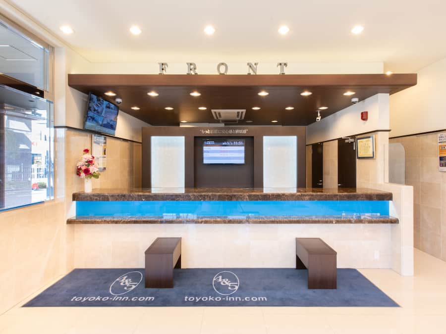 A reception desk with a digital screen, a wooden counter, and a sign that reads "FRONT".